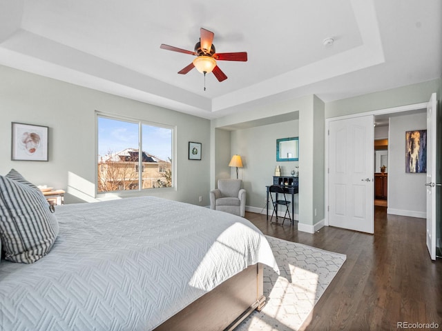 bedroom featuring dark wood-type flooring, ceiling fan, and a raised ceiling