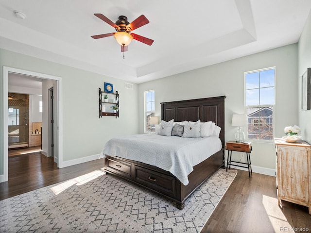 bedroom with dark hardwood / wood-style flooring, ceiling fan, and a raised ceiling