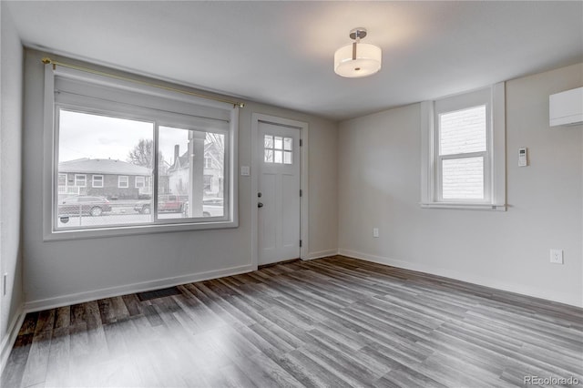 foyer featuring an AC wall unit, plenty of natural light, and hardwood / wood-style flooring