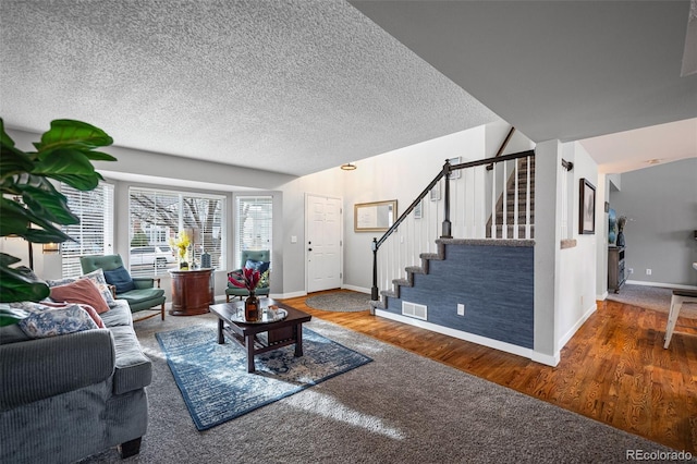 living area with baseboards, visible vents, dark wood-style flooring, stairs, and a textured ceiling