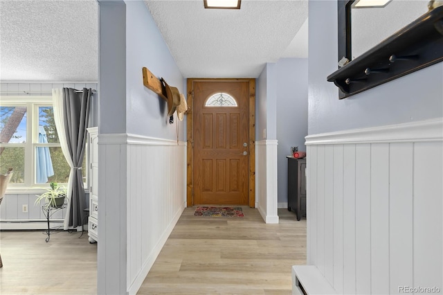 entryway with a textured ceiling, a baseboard radiator, and light hardwood / wood-style flooring