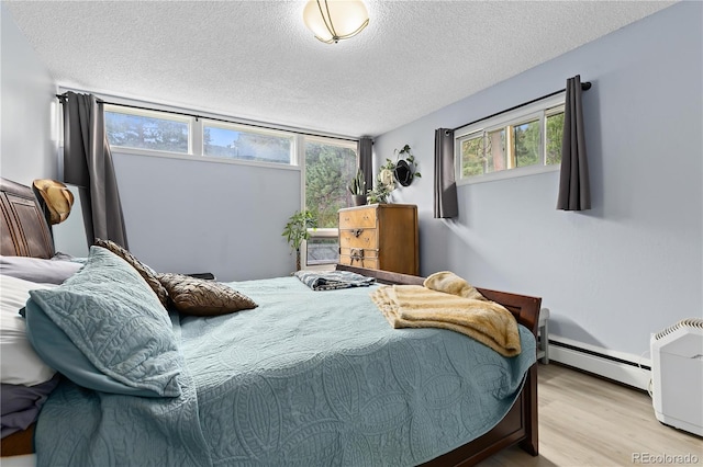 bedroom featuring a textured ceiling, light wood-type flooring, and baseboard heating