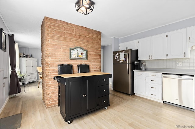 kitchen featuring light wood-type flooring, tasteful backsplash, stainless steel appliances, crown molding, and white cabinetry