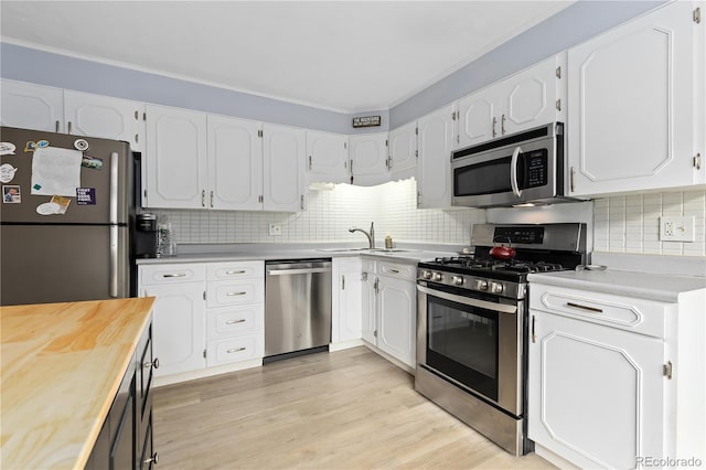 kitchen featuring white cabinets, stainless steel appliances, butcher block countertops, and light hardwood / wood-style flooring