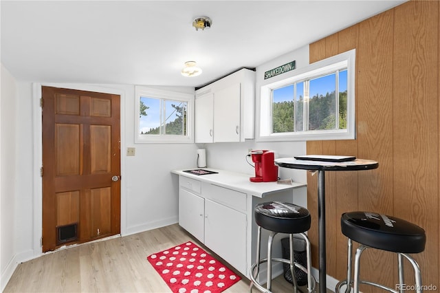 kitchen with a kitchen breakfast bar, light hardwood / wood-style flooring, white cabinetry, and lofted ceiling