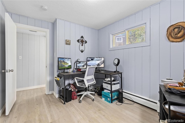 office area with light wood finished floors, baseboards, a baseboard heating unit, and a textured ceiling