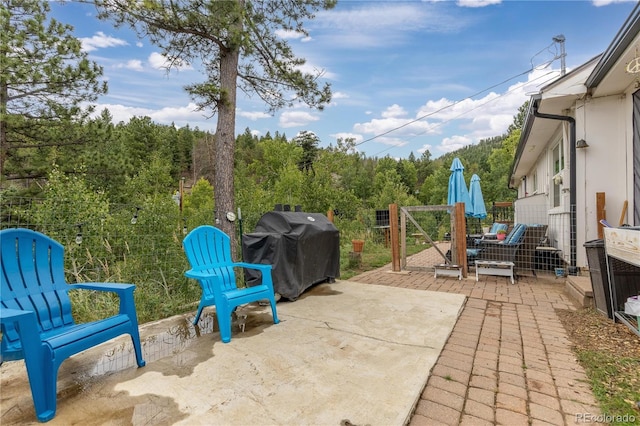 view of patio with area for grilling, fence, and a gate