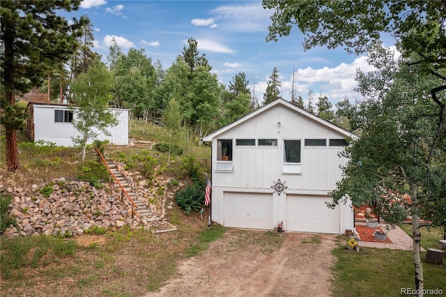 exterior space featuring board and batten siding and dirt driveway