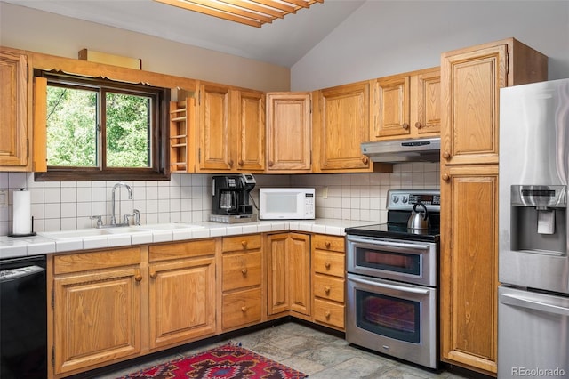 2246 Gcr 8, Fraser, CO 80442 - kitchen featuring appliances with stainless steel finishes, under cabinet range hood, vaulted ceiling, and decorative backsplash