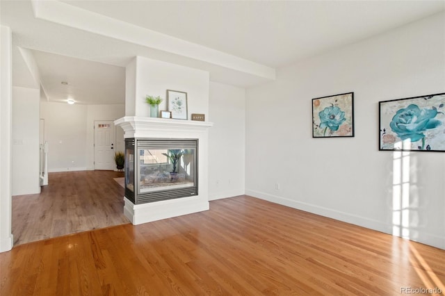 unfurnished living room with hardwood / wood-style flooring and a multi sided fireplace