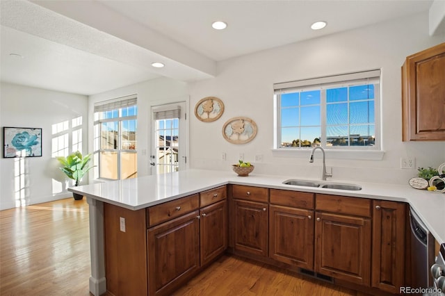 kitchen featuring dishwasher, sink, light wood-type flooring, and kitchen peninsula