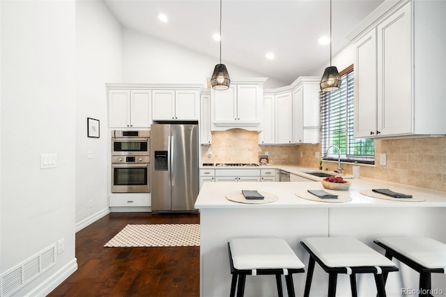3320 Yukon Ct, Wheat Ridge, CO 80033 - kitchen featuring appliances with stainless steel finishes, a sink, dark wood-type flooring, a peninsula, and light countertops