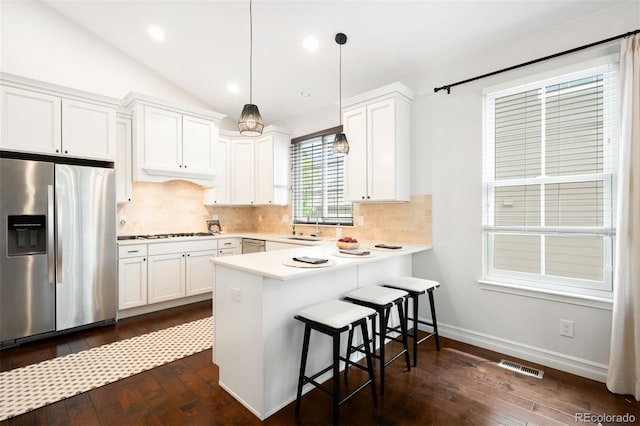 3320 Yukon Ct, Wheat Ridge, CO 80033 - kitchen featuring stainless steel appliances, dark wood-style flooring, decorative backsplash, a breakfast bar, and a peninsula