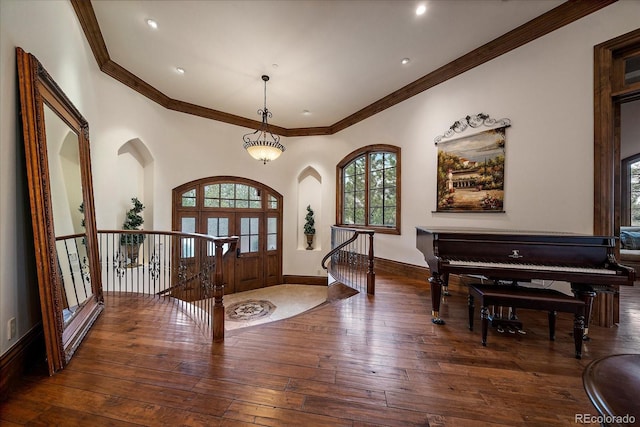 entryway featuring arched walkways, ornamental molding, dark wood-style flooring, and baseboards