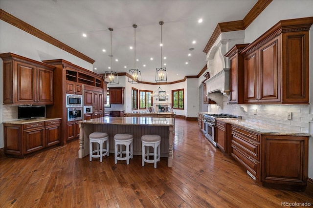 kitchen with light stone countertops, dark wood-type flooring, appliances with stainless steel finishes, a center island, and pendant lighting