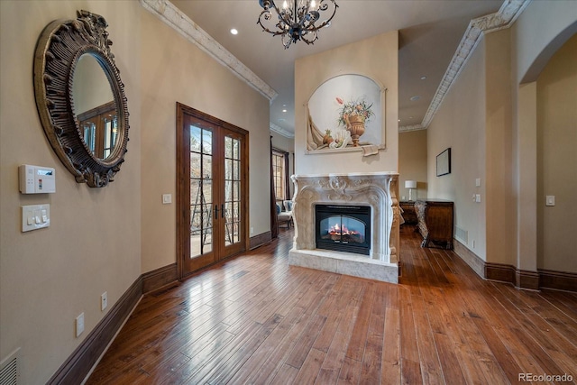 unfurnished living room with french doors, crown molding, a high end fireplace, baseboards, and hardwood / wood-style flooring