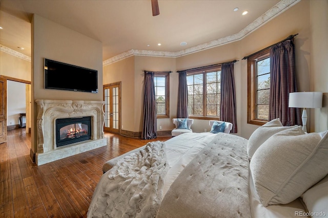 bedroom with crown molding, hardwood / wood-style floors, a premium fireplace, and baseboards