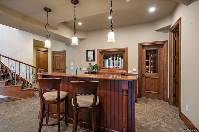 bar featuring dark tile patterned floors, visible vents, stairs, hanging light fixtures, and wet bar