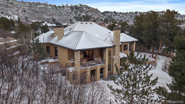 exterior space featuring stone siding, a mountain view, a chimney, and stucco siding