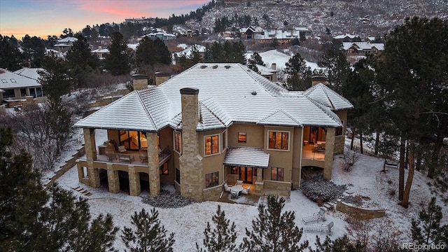 snow covered rear of property with stone siding