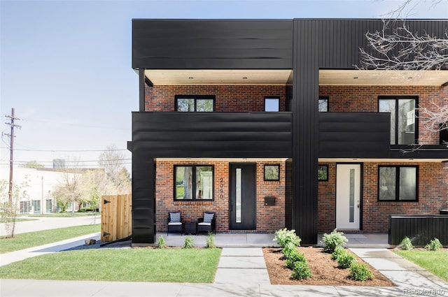 view of front of house featuring covered porch, brick siding, and a balcony
