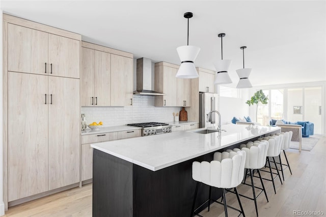 kitchen with wall chimney range hood, stove, light wood-style flooring, a spacious island, and light brown cabinetry