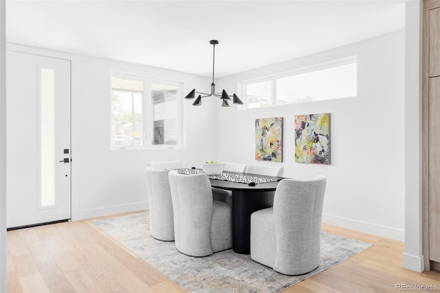 dining space with a chandelier, wood finished floors, and baseboards