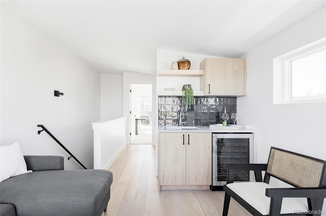 indoor bar featuring beverage cooler, light wood-type flooring, and decorative backsplash