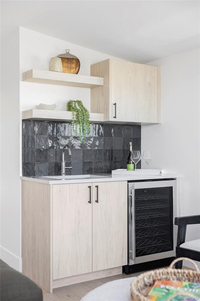 indoor bar featuring beverage cooler, decorative backsplash, and wood finished floors