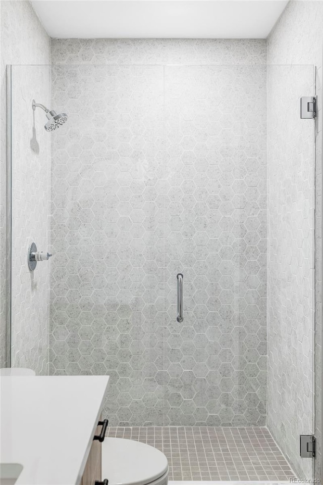 full bathroom with toilet, a stall shower, and vanity