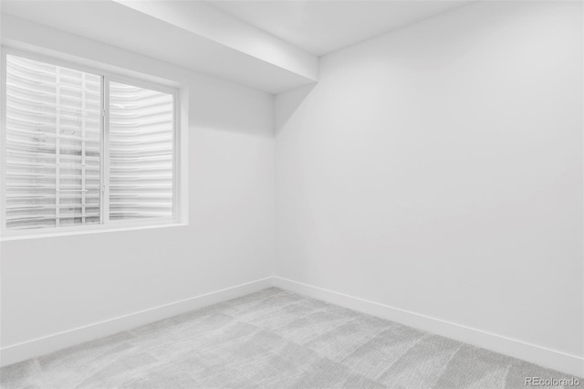 spare room with light colored carpet and baseboards