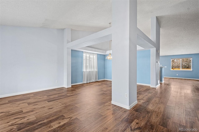 spare room with a textured ceiling, dark wood-type flooring, and a wealth of natural light