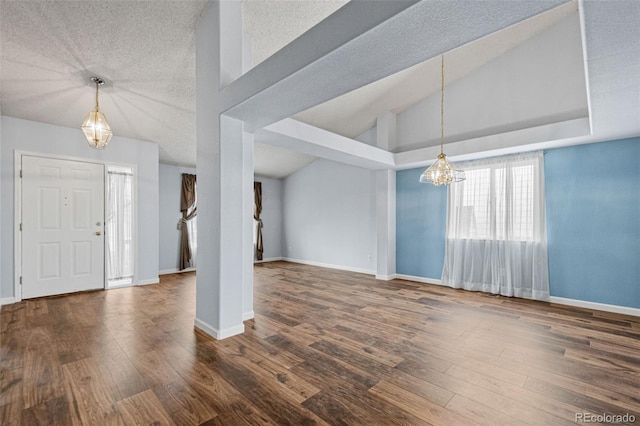 entrance foyer with dark hardwood / wood-style flooring, lofted ceiling, and a notable chandelier