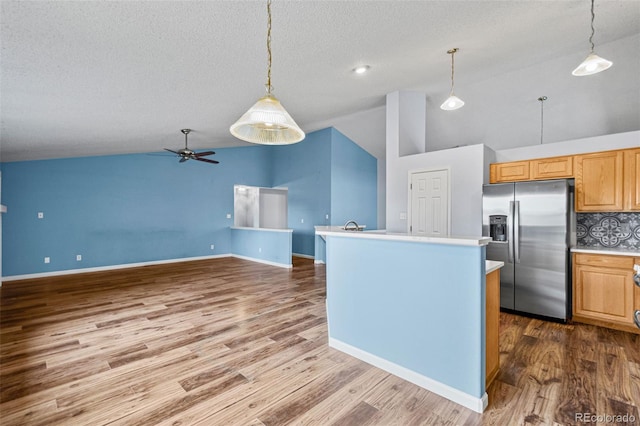 kitchen featuring decorative light fixtures, tasteful backsplash, stainless steel fridge with ice dispenser, ceiling fan, and a center island with sink