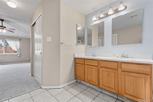 bathroom featuring ceiling fan, vanity, tile patterned flooring, and a textured ceiling