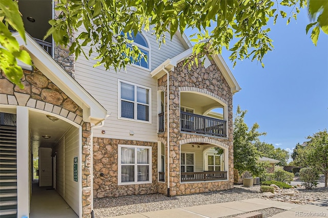 view of front of property featuring a balcony and central AC unit