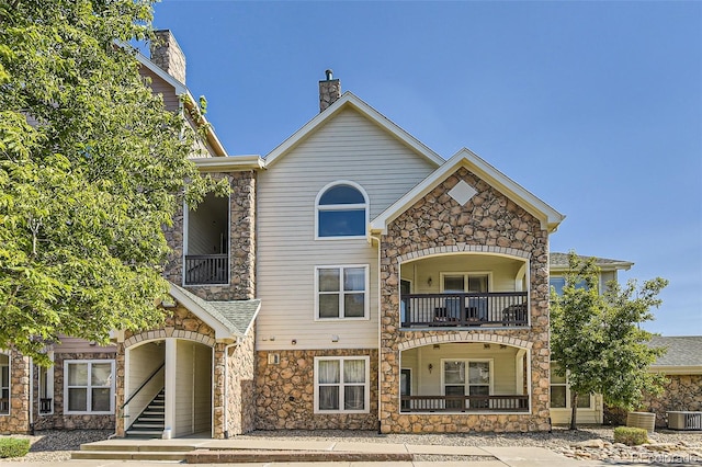 view of front of home featuring a balcony and central air condition unit