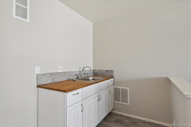 interior space featuring butcher block countertops, sink, and white cabinets