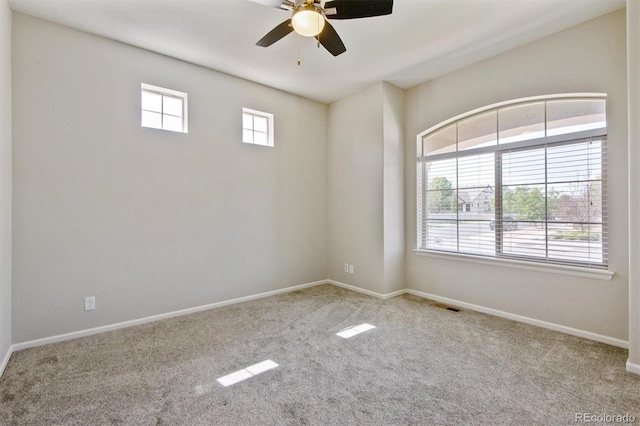 empty room with light carpet, ceiling fan, and a healthy amount of sunlight