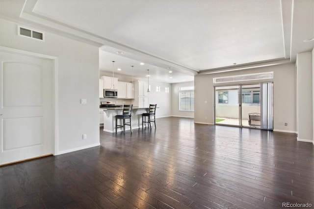 living room with dark wood-style flooring, a raised ceiling, visible vents, and baseboards