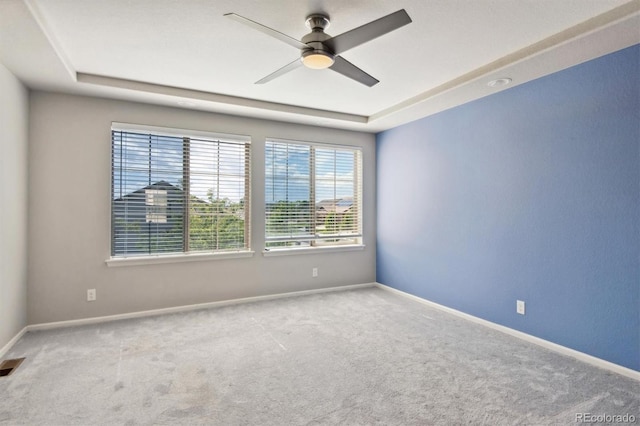 spare room with visible vents, baseboards, a raised ceiling, a ceiling fan, and carpet