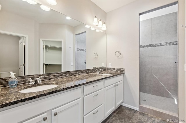 full bath featuring a spacious closet, a sink, a tile shower, and double vanity