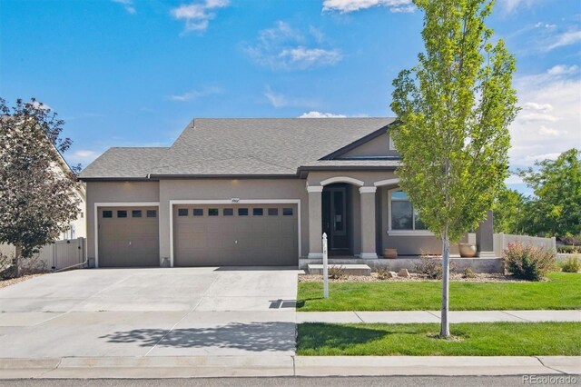 view of front facade with a garage, driveway, a front yard, and stucco siding