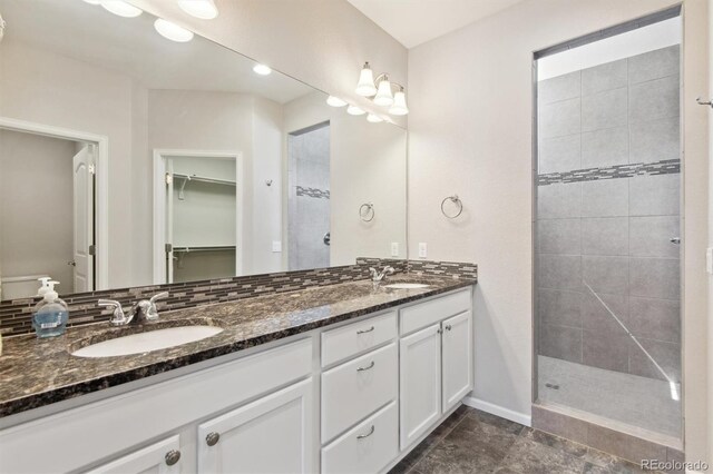 19802 E 54th Ave, Denver, CO 80249 - bathroom with double vanity, a walk in closet, tiled shower, and baseboards