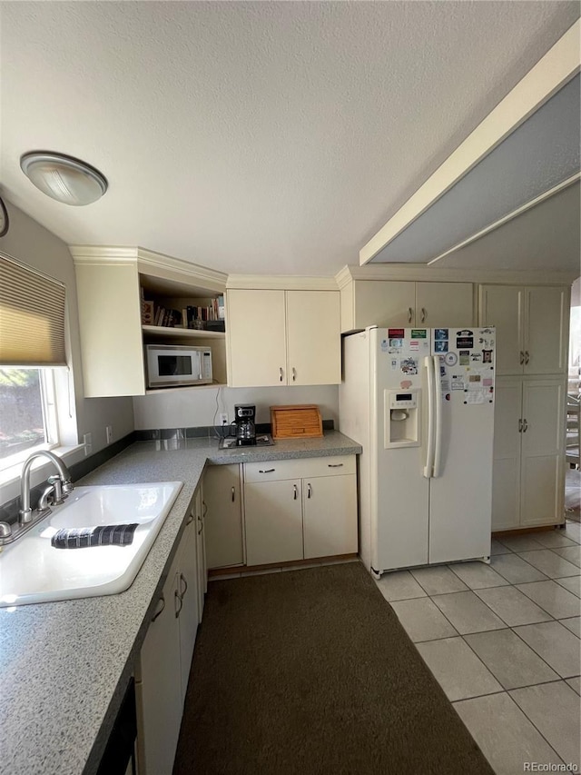 kitchen featuring sink, light tile patterned floors, a textured ceiling, and white appliances