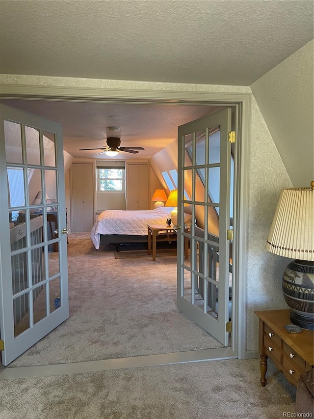 bedroom with ceiling fan, carpet floors, vaulted ceiling, and a textured ceiling