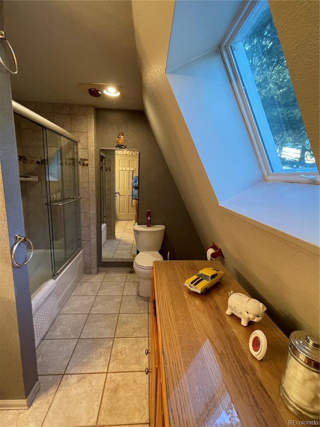 bathroom featuring toilet, a skylight, tile patterned flooring, and combined bath / shower with glass door