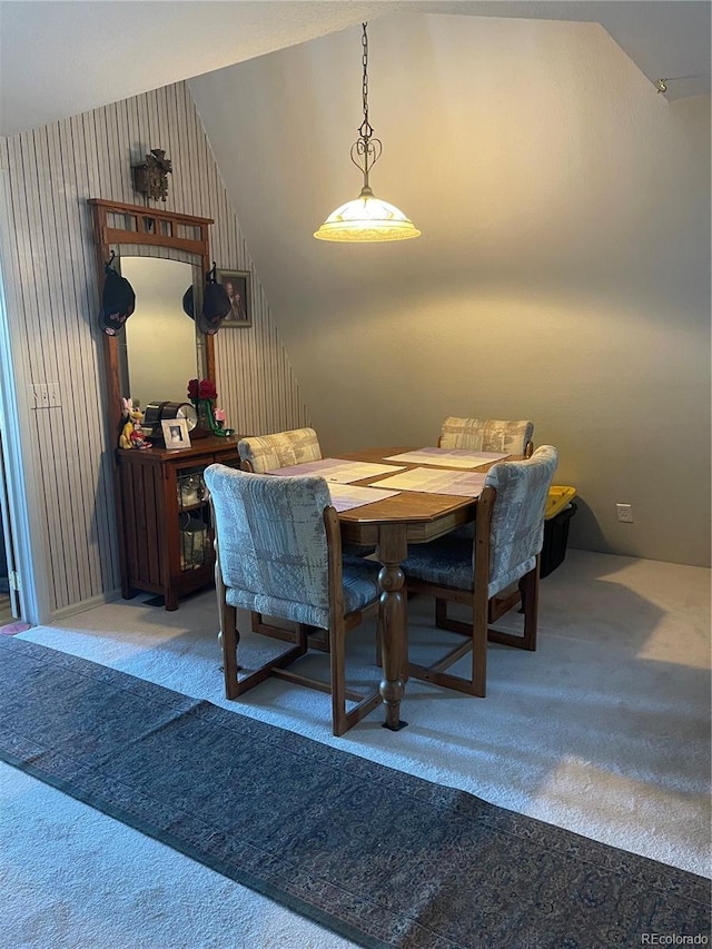 carpeted dining space with vaulted ceiling