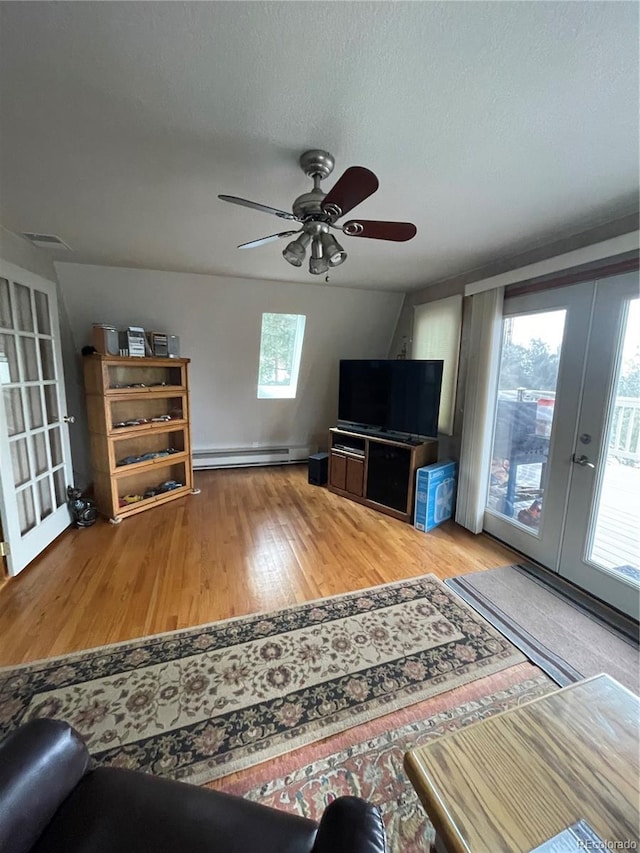 unfurnished living room featuring ceiling fan, baseboard heating, hardwood / wood-style floors, a textured ceiling, and french doors