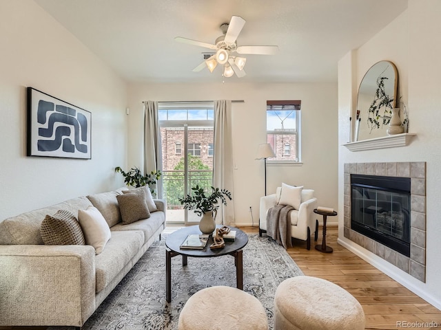 5467 Zephyr Ct Unit 5467, Arvada, CO 80002 - living area featuring light wood-style floors, a tiled fireplace, a ceiling fan, and baseboards